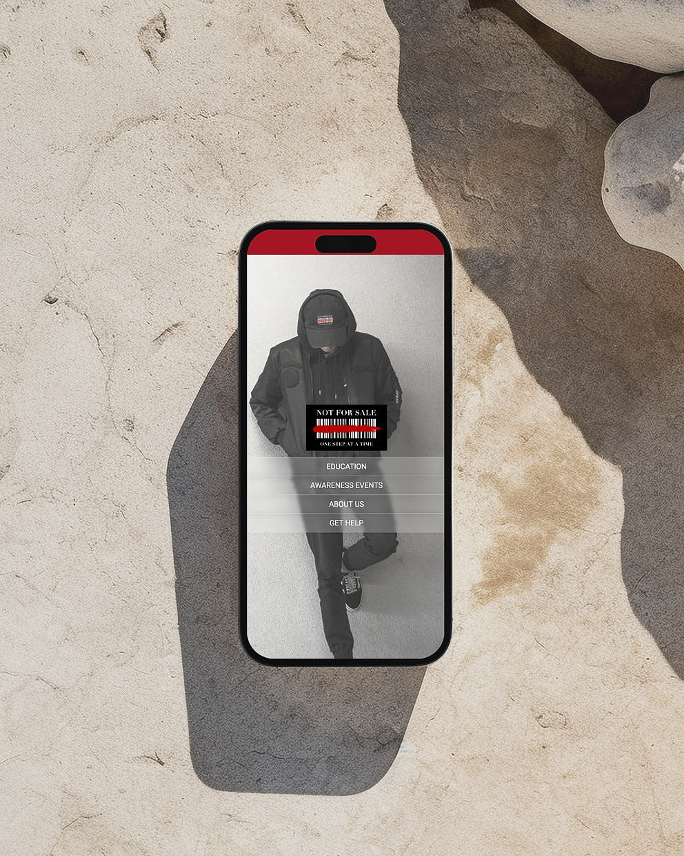 Smartphone mockup showing the Not For Sale website menu on a stone background.