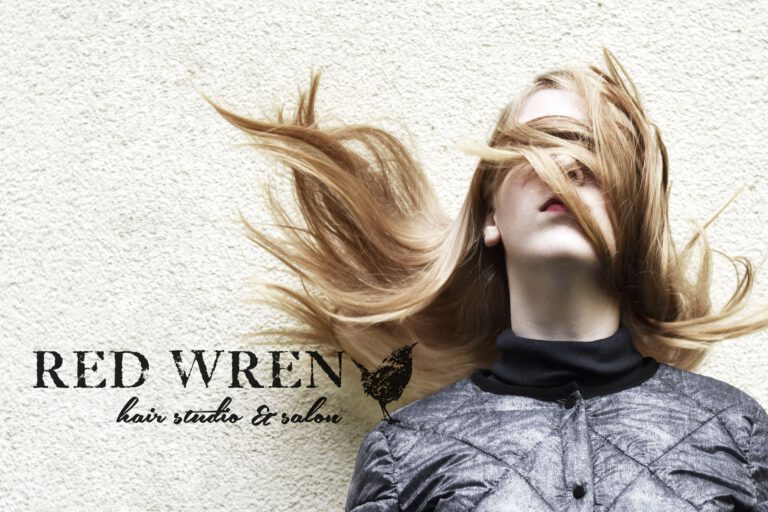 Red Wren Hair logo design reading “RED WREN” with a bird icon and the tagline “hair studio & salon,” over a photo of a woman with windswept hair. Brand identity provided by Rebecca Snyder, lead graphic artist at A LA MODE designs, an award-winning design studio, located in Canton, Ohio.