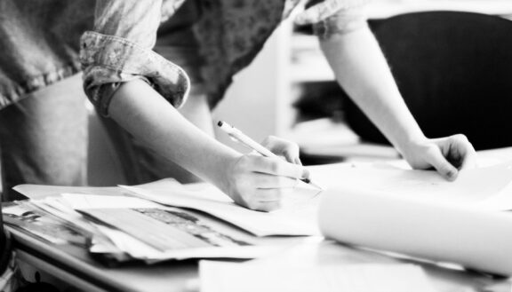Hands of a designer sketching concepts on paper at a worktable, representing award-winning graphic design.