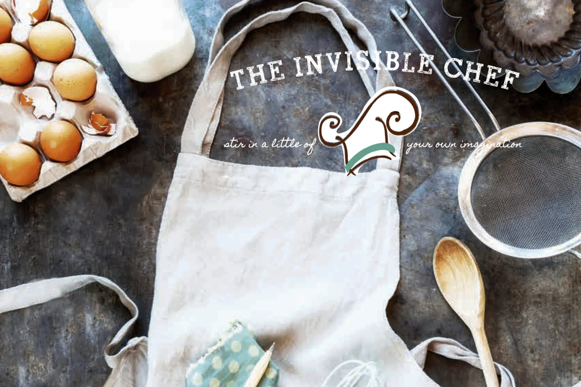 The Invisible Chef logo over a baking flat-lay with an apron, eggs, sieve, and wooden spoon.
